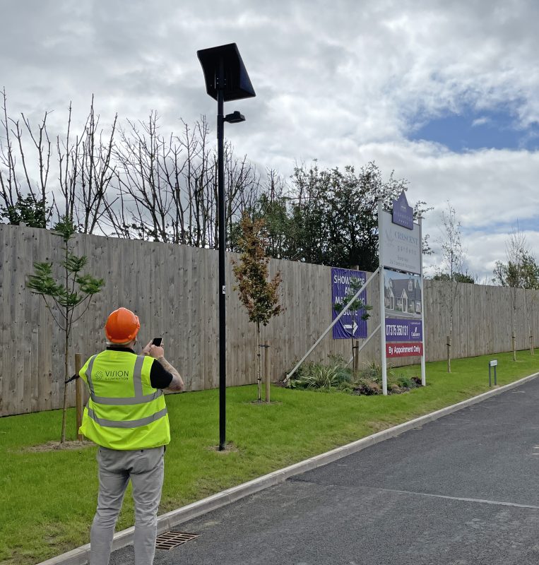 A lighting engineer programs a solar street light via remote control.