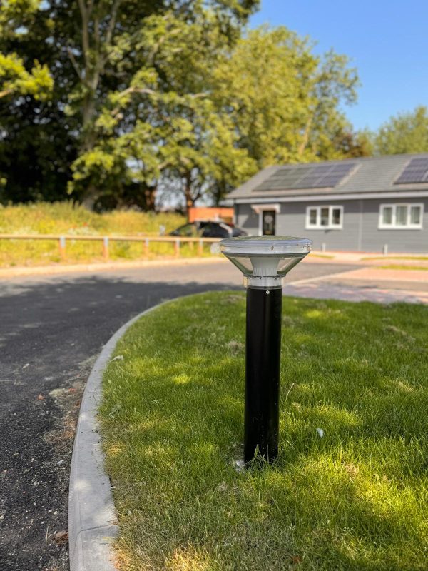 Solar powered bollard set into a grass verge in a commercial setting.
